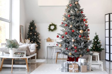 Oturma odasının içinde Noel ağaçları ve hediyeler var.