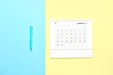 Ocak 2022 için kağıt takvim ve mavi ve sarı arkaplan üzerine kalem