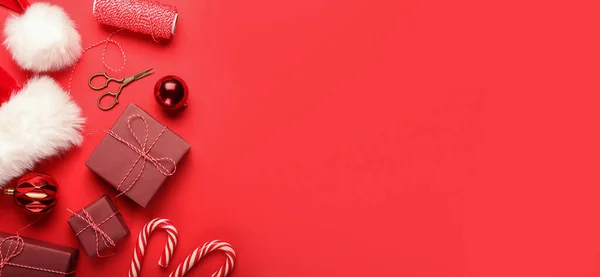 Weihnachtsgeschenke Mit Weihnachtsmütze Und Dekorationen Auf Rotem Hintergrund Mit Platz — Stockfoto
