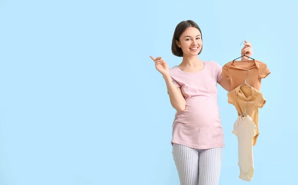 Young Pregnant Woman Baby Bodysuits Pointing Something Blue Background — Stock Photo, Image