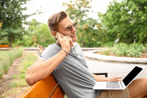Jovem Óculos Sol Com Laptop Conversando Por Telefone Celular Banco — Fotografia de Stock