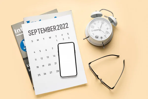 2022年9月の携帯電話 紙カレンダー 目覚まし時計 眼鏡の色背景 — ストック写真
