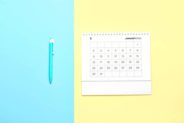 Календарь флип-бумаги на январь 2022 года и ручка на синем и желтом фоне