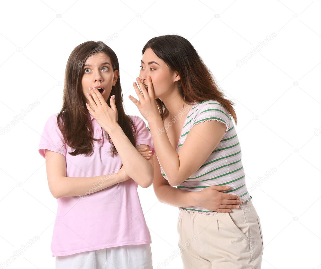 Young gossiping women on white background
