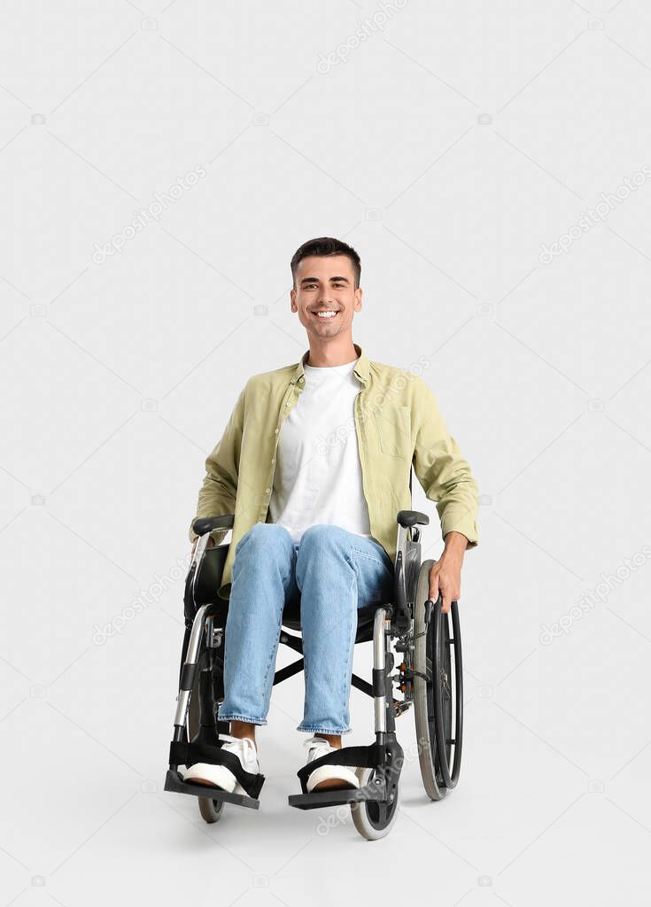Young man in wheelchair on light background