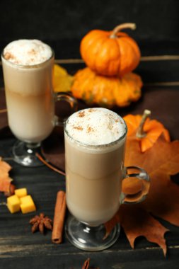 Koyu ahşap zemin üzerinde cam bardaklar dolusu lezzetli balkabaklı latte.