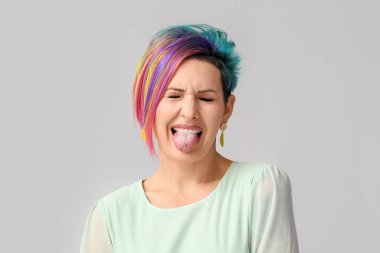 Grimsi arka planda alışılmadık saçları olan suratsız bir kadın.