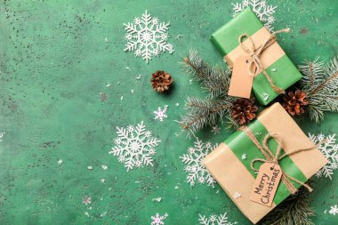 Güzel kar taneleri, köknar dalları ve yeşil arka planda hediye kutuları.