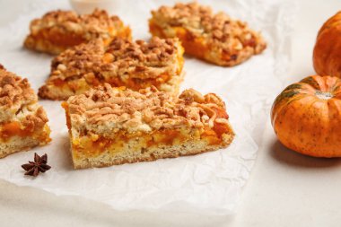 Beyaz arkaplanda lezzetli balkabağı turtası parçaları olan parşömen.