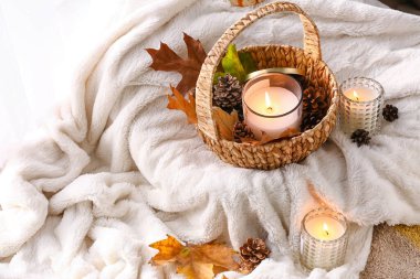 Tutucularda mum yakmak ve odada yumuşak ekose üzerinde sonbahar dekoru.