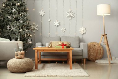 İçinde Noel ağacı, kar taneleri ve parıldayan ışıklar olan şık bir oturma odası.