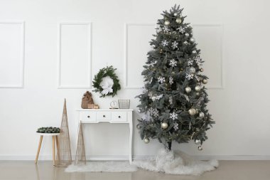 Beyaz duvarın yanında Noel ağacı ve dekor olan bir oda.
