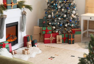 Modern şömine ve hediye kutuları şenlikli oturma odasındaki Noel ağacının altında.