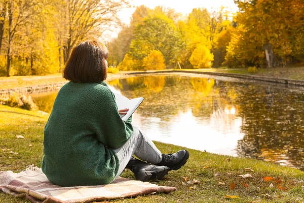 Młoda Kobieta Siedzi Kratce Czyta Książkę Pobliżu Stawu Jesiennym Parku — Zdjęcie stockowe