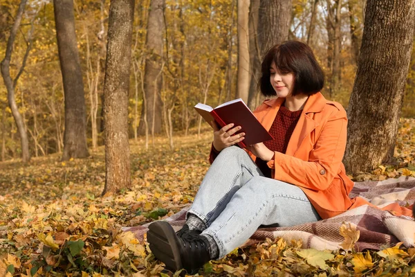 Młoda Kobieta Siedzi Kratę Pobliżu Drzewa Czyta Książkę Jesiennym Parku — Zdjęcie stockowe