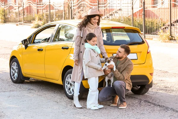 Happy family with cute dog near yellow car outdoors