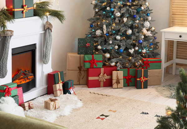 Modern fireplace and gift boxes under Christmas tree in festive living room