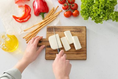 Mutfaktaki masada peynir kesen kadın.