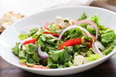 Arka planda sağlıklı Yunan salatası tabağı, yakın plan.