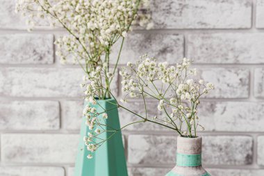 Tuğla arka planda güzel çingene çiçekleri olan vazolar, yakın plan.