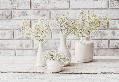 Tuğla duvarın yanındaki ahşap masada güzel çingene çiçekleriyle vazolar.