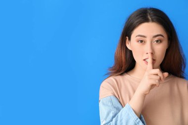 Genç Asyalı kadın arka planda sessizlik jesti yapıyor