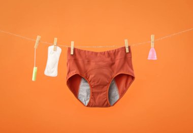 Adet külotu, ped, regl kupası ve ipe asılı tampon renk arkaplan