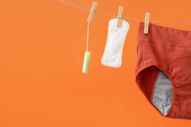 Adet külotu, tampon ve ped ipe asılı renk arkaplan, yakın plan