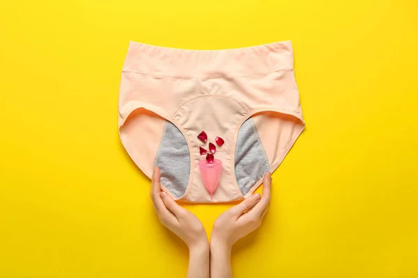 Mãos Femininas Com Calcinha Período Copo Menstrual Pétalas Rosa Fundo — Fotografia de Stock