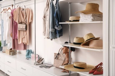 Farklı hasır şapkalar, şık ayakkabılar ve butikte giyilen kıyafetler.