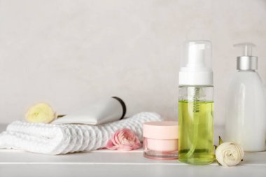 Kozmetik ve ranunculus çiçekli şişeler ahşap masada.