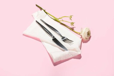 Çatal bıçak takımı, peçete ve ranunculus çiçeği.