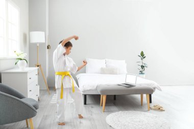 Küçük çocuk evde online karate okuyor.