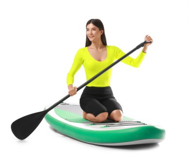 Sörf tahtası olan ve beyaz arka planda kürek çeken genç bir kadın.