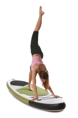 Beyaz arka planda yemek masasında yoga yapan genç bir kadın.