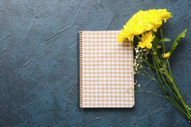 Sarı kasımpatı çiçekleri ve koyu arkaplanda not defteri