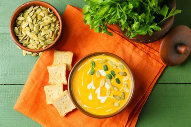 Lezzetli balkabağı kremalı çorba, tohumlar ve ahşap arka planda kızarmış ekmek.