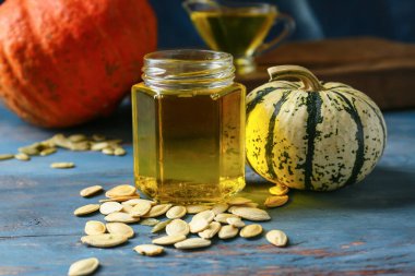 Renkli ahşap arka planda bir kavanoz kabak tohumu yağı, yakın plan.