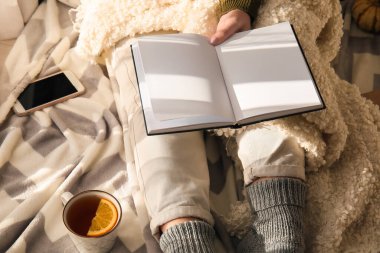 Kadın yerde oturuyor ve elinde boş sayfalarla açık bir kitap tutuyor.