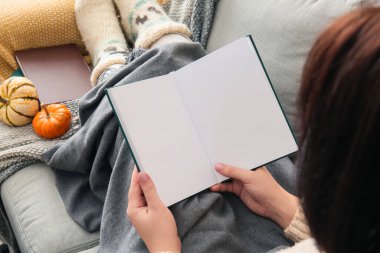 Kanepede oturan ve elinde boş sayfaları olan bir kadın.