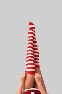 Açık arkaplanda Noel çoraplı seksi genç kadın bacakları.