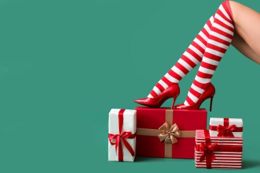 Noel çoraplı seksi genç bir kadın ve renk arka planında hediye kutuları var.