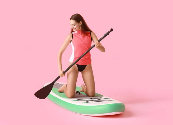 Sportliche Junge Frau Mit Surfbrett Und Ruder Auf Farbigem Hintergrund — Stockfoto