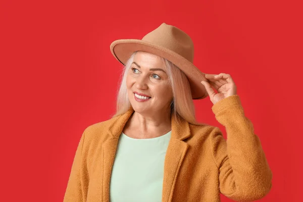 Μοντέρνα Ώριμη Γυναίκα Φορώντας Καπέλο Τσόχινο Κόκκινο Φόντο — Φωτογραφία Αρχείου