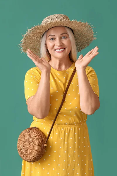 幸せな成熟した女性でわら帽子でスタイリッシュなバッグ上の緑の背景 — ストック写真