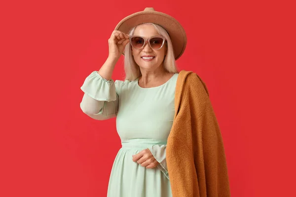 Modna Dojrzała Kobieta Filcowym Kapeluszu Okularach Przeciwsłonecznych Czerwonym Tle — Zdjęcie stockowe