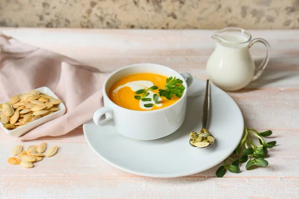 Lezzetli kabak kremalı çömlek ve beyaz ahşap masada tohumlar.