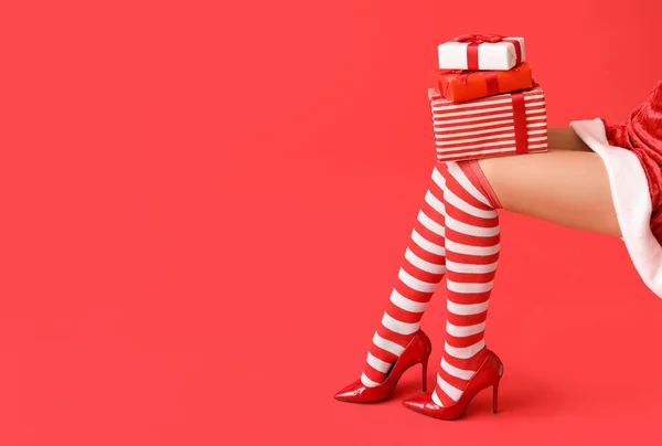セクシーな若い女性でクリスマスストッキングとギフト上の色の背景 — ストック写真