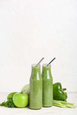 Hafif arkaplanda sağlıklı yeşil meyve suyu ve sebze şişeleri