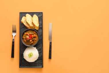 Lezzetli körili kase, renkli arkaplanda ekmek ve pirinç.